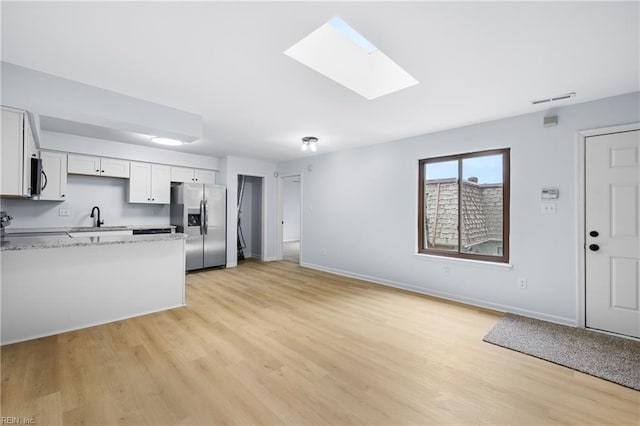 kitchen with light stone counters, a sink, visible vents, appliances with stainless steel finishes, and light wood-type flooring