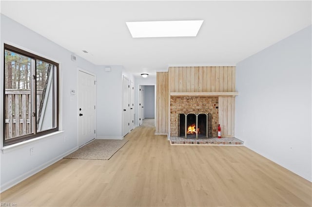 unfurnished living room with light wood-type flooring, a fireplace, and baseboards