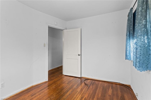 empty room featuring baseboards and wood finished floors