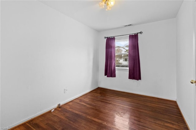 unfurnished room featuring baseboards, visible vents, and wood finished floors