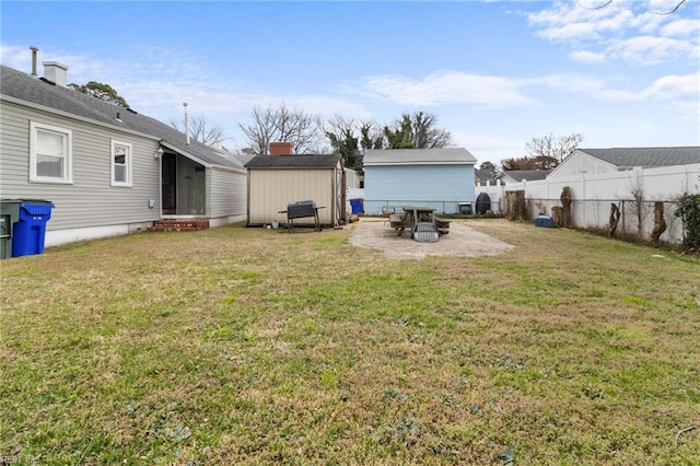 view of yard with a storage shed, a patio area, an outdoor structure, and fence