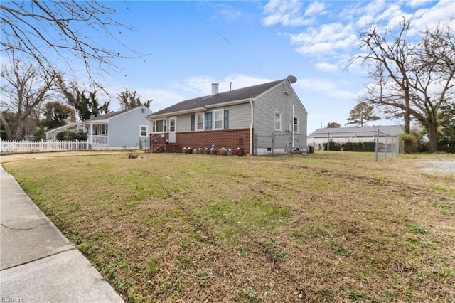 view of front of home with a chimney, fence, a front lawn, and brick siding