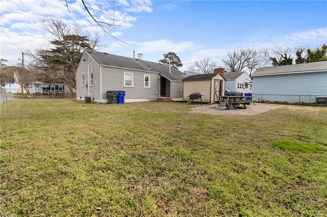 back of property featuring an outbuilding, fence, a lawn, and a storage unit