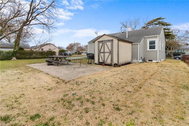 exterior space featuring a yard, a patio area, an outdoor structure, and a storage unit