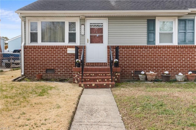 view of front facade featuring entry steps, roof with shingles, brick siding, and crawl space