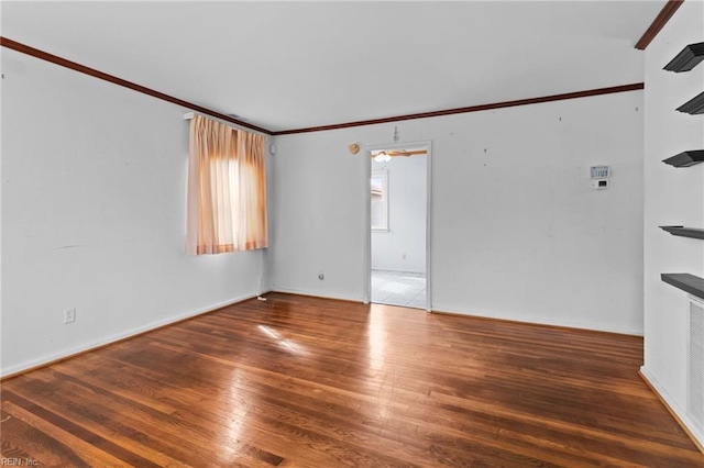 spare room with ornamental molding and wood finished floors