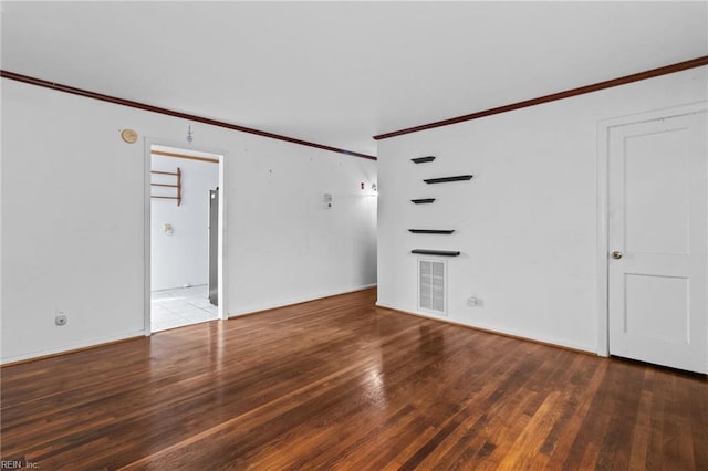 empty room with visible vents, hardwood / wood-style floors, and ornamental molding