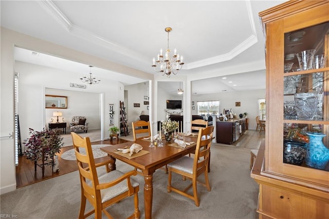 dining room with ornamental molding, a tray ceiling, light carpet, and a fireplace