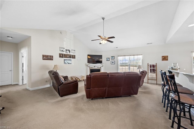 living area with light carpet, baseboards, ceiling fan, vaulted ceiling, and a fireplace