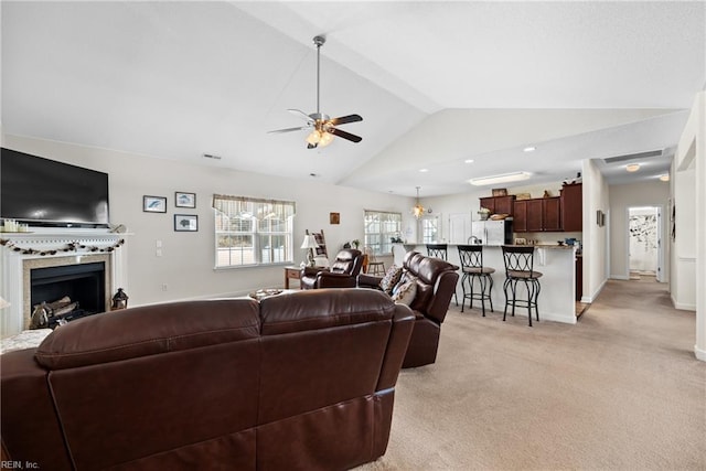 living area with light carpet, visible vents, lofted ceiling, ceiling fan, and a fireplace