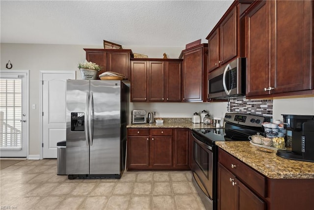 kitchen with tasteful backsplash, light stone counters, stainless steel appliances, and a textured ceiling