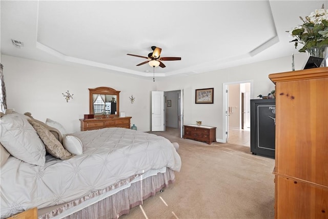 bedroom featuring a ceiling fan, a raised ceiling, visible vents, and light colored carpet