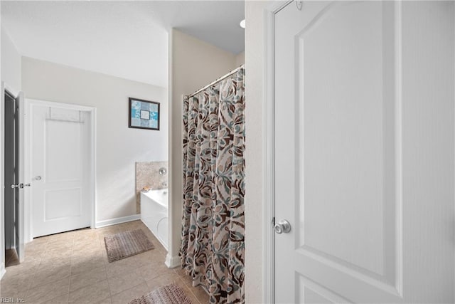 bathroom with tile patterned flooring, a bath, and baseboards