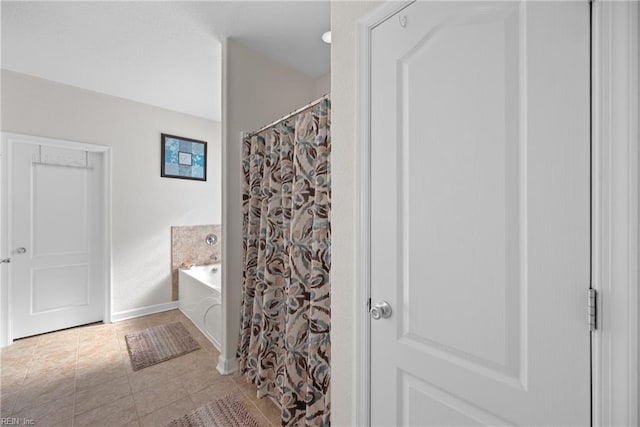 bathroom with tile patterned flooring, a garden tub, and baseboards