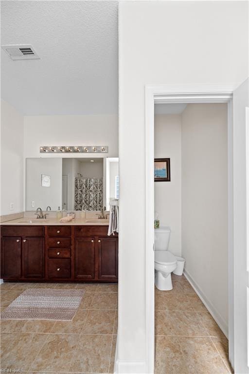 full bath with double vanity, visible vents, toilet, a sink, and tile patterned flooring