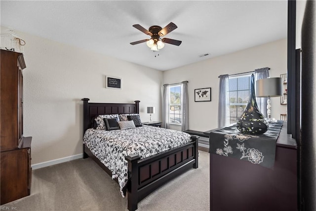 bedroom with light colored carpet, ceiling fan, visible vents, and baseboards