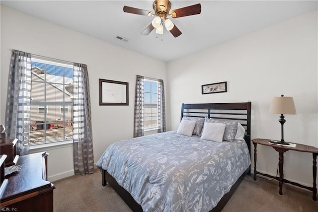 carpeted bedroom with ceiling fan, multiple windows, visible vents, and baseboards