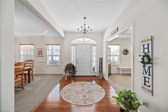 foyer entrance featuring a notable chandelier, plenty of natural light, wood-type flooring, and a textured ceiling