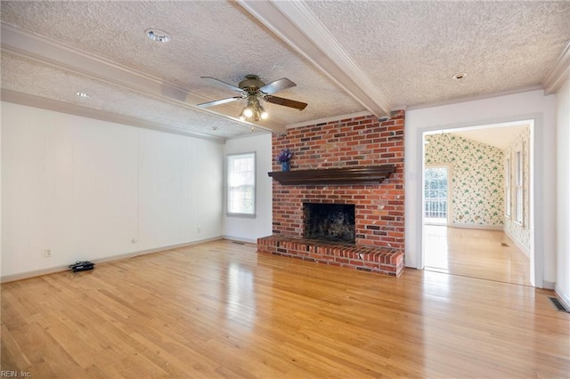 unfurnished living room with a textured ceiling, a fireplace, wood finished floors, and beam ceiling