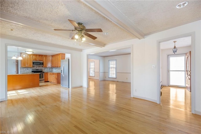 unfurnished living room with a textured ceiling, a ceiling fan, baseboards, light wood-style floors, and beamed ceiling