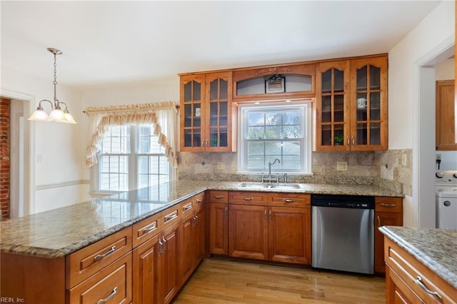 kitchen with brown cabinets, dishwasher, a peninsula, and a sink