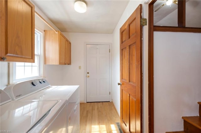 laundry room featuring washing machine and dryer, cabinet space, and light wood-style floors