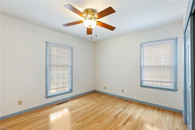 empty room featuring light wood finished floors, baseboards, visible vents, and ceiling fan