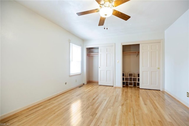 unfurnished bedroom with multiple closets, light wood-style flooring, baseboards, and a ceiling fan