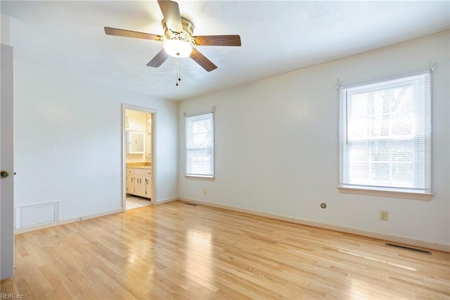 unfurnished bedroom featuring ceiling fan, connected bathroom, visible vents, baseboards, and light wood finished floors