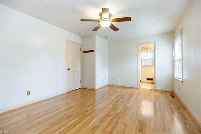 unfurnished room featuring baseboards, light wood-style flooring, visible vents, and a ceiling fan