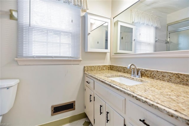 bathroom with a stall shower, visible vents, vanity, and toilet