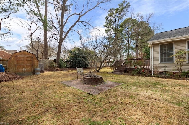 view of yard with an outbuilding, a fire pit, fence, a wooden deck, and a storage unit