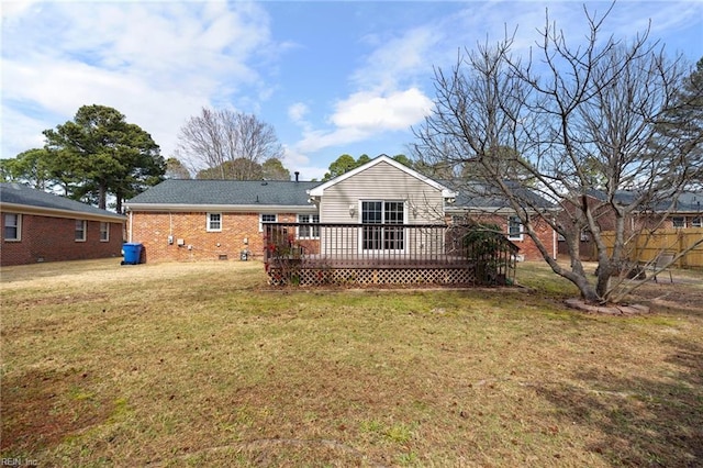 rear view of property featuring crawl space, brick siding, a lawn, and a deck