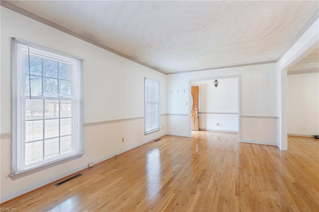 spare room with crown molding, visible vents, a textured ceiling, light wood-type flooring, and baseboards