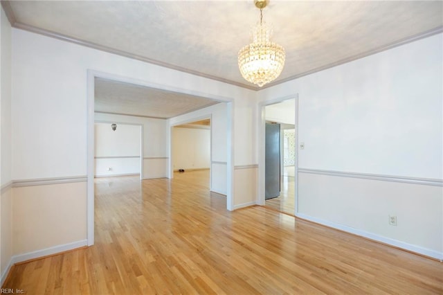 unfurnished room featuring ornamental molding, a chandelier, baseboards, and light wood finished floors