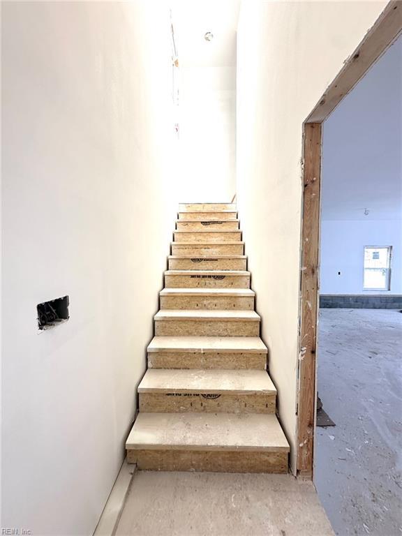 staircase featuring unfinished concrete flooring