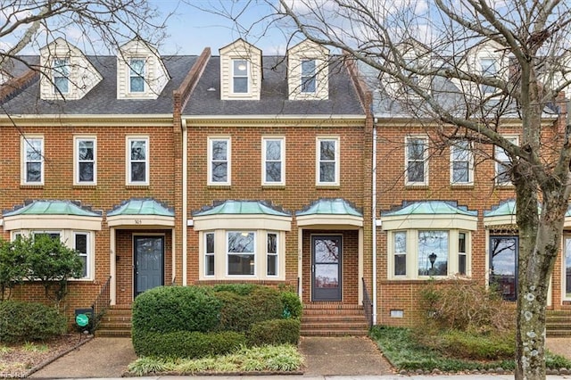 multi unit property featuring a shingled roof and brick siding