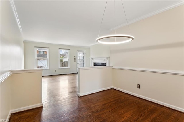 spare room with baseboards, a fireplace, ornamental molding, and wood finished floors