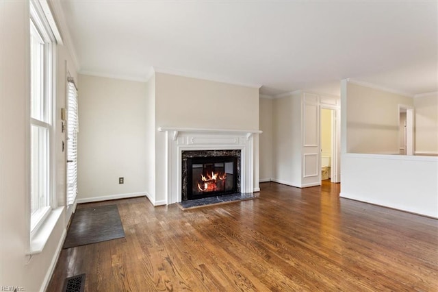 unfurnished living room featuring a healthy amount of sunlight, a premium fireplace, visible vents, and wood finished floors