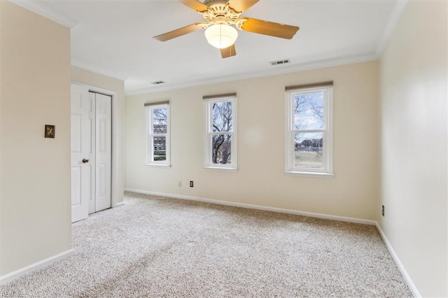 carpeted empty room featuring baseboards, visible vents, and crown molding