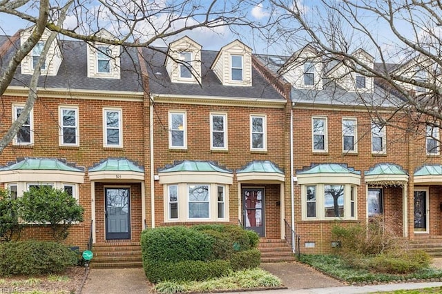 townhome / multi-family property with a shingled roof and brick siding