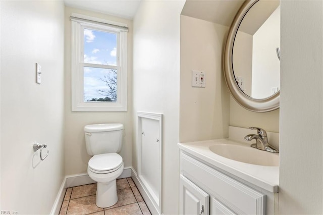 half bath with toilet, vanity, baseboards, and tile patterned floors