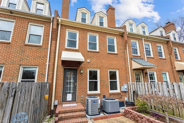 multi unit property with fence, central AC unit, and brick siding