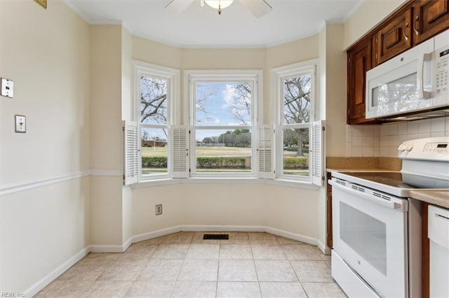 kitchen featuring light tile patterned floors, white appliances, backsplash, and a healthy amount of sunlight