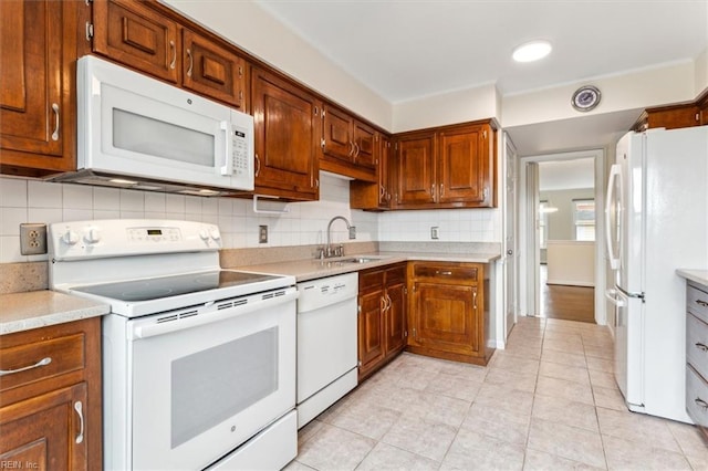 kitchen featuring light tile patterned floors, light countertops, backsplash, a sink, and white appliances