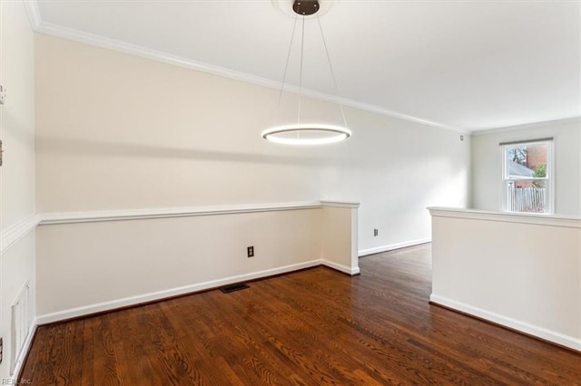 empty room featuring ornamental molding, visible vents, baseboards, and wood finished floors