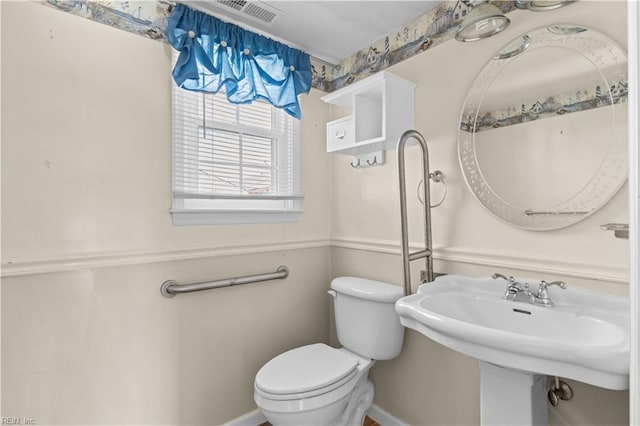 bathroom with toilet, visible vents, and a sink