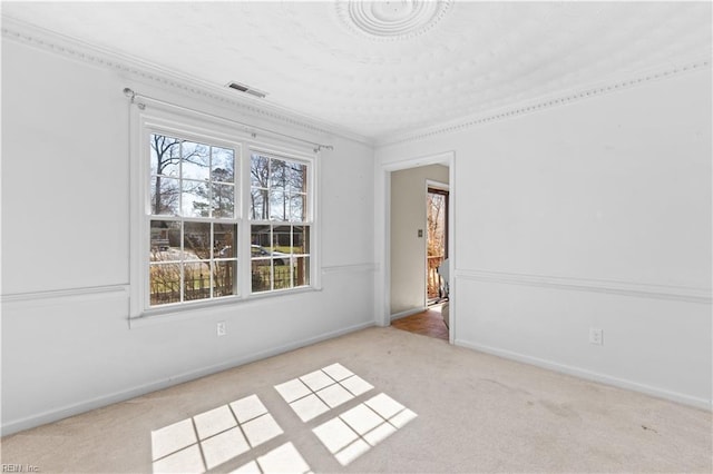 empty room featuring carpet floors, baseboards, visible vents, and crown molding