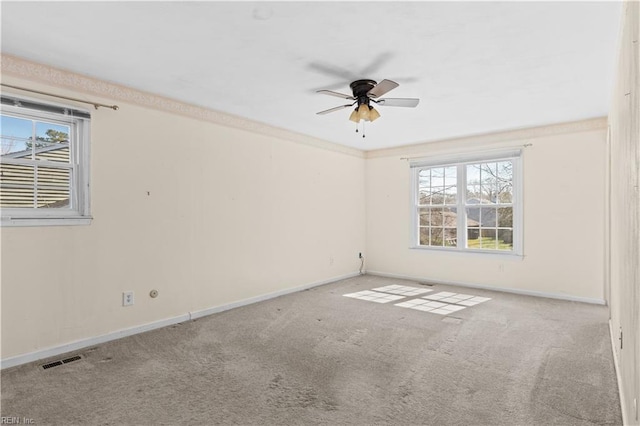 carpeted empty room featuring a ceiling fan, visible vents, and baseboards