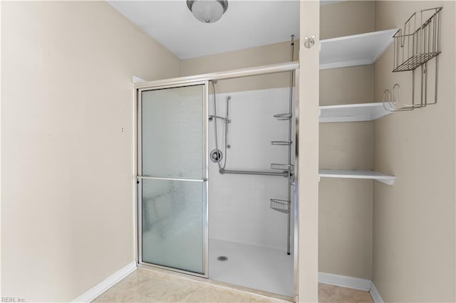 bathroom with a shower stall and baseboards